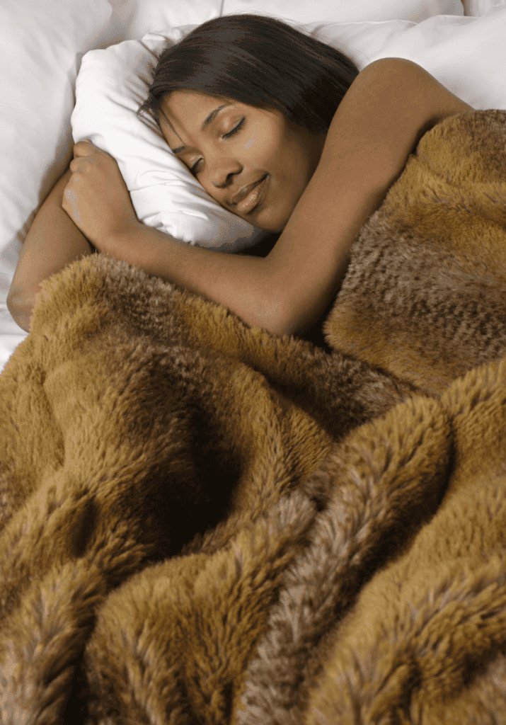 A woman sleeping in a brown rug-like blanket showcasing the need for rest especially after participating in fitness
