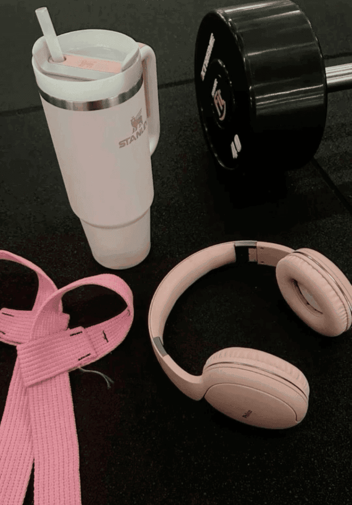 showing items used for a fitness transformation journey such a stanley cup, dumbbell, headphones, etc;