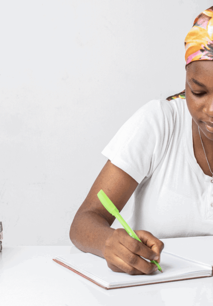 A woman writing down notes in a book to show she is participating in self-care