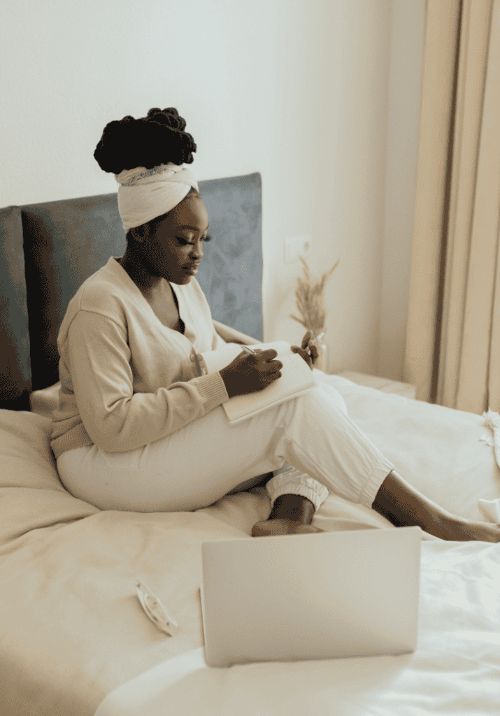 black woman in cozy clothing planning in her planner