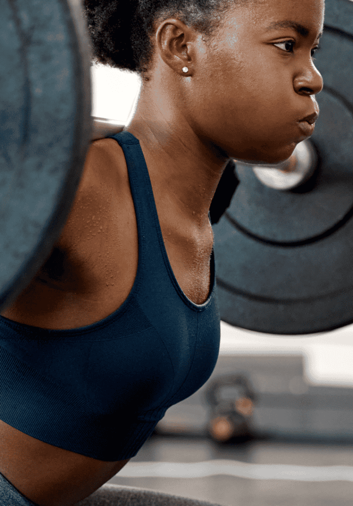 a black woman holding a barbell and working out to reach her goals