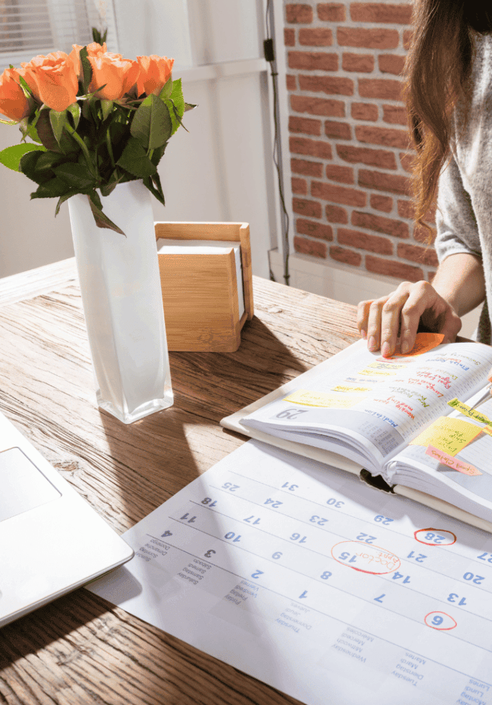 Image of a woman working in her planning, trying to align her passion and productivity! The planner is color-coded.