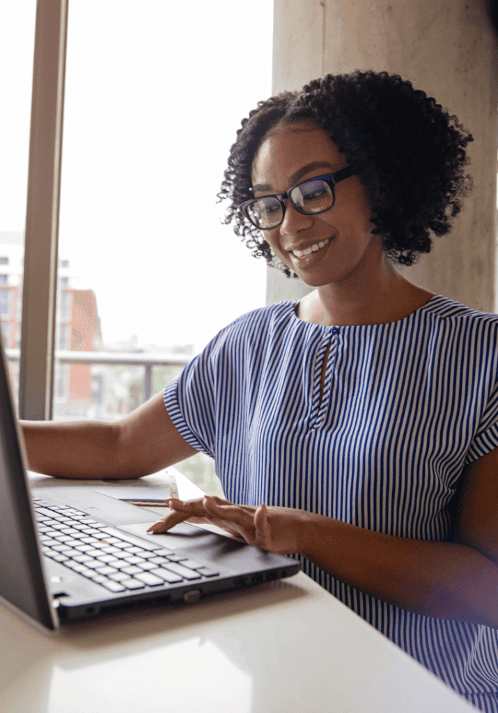 a woman with curly natural hair working on her laptop.