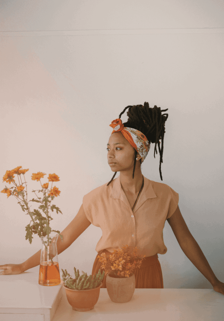 a woman looking over her shoulder contemplating body image and self-compassing, with plants in front of her.