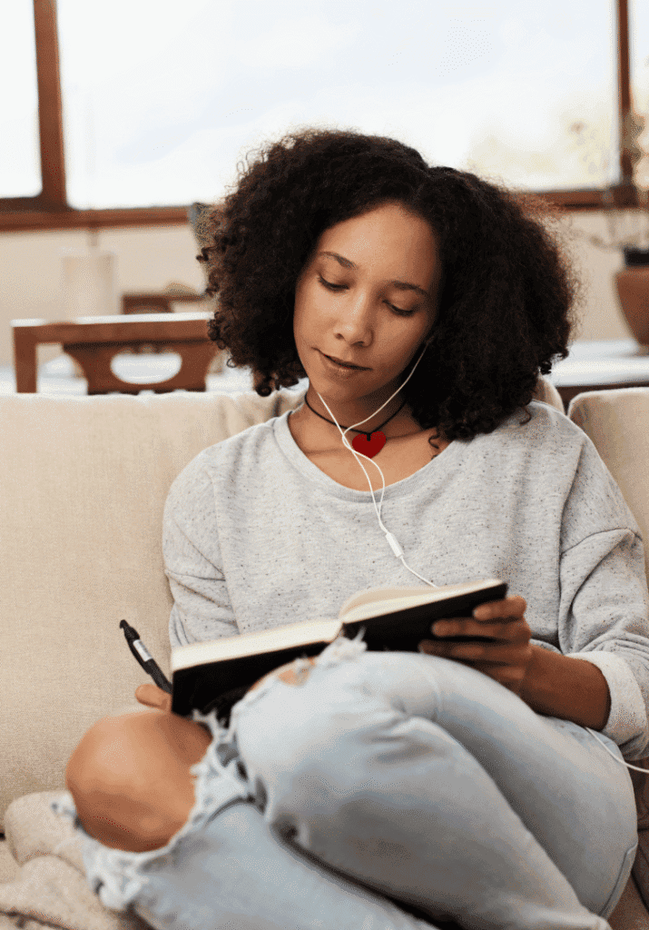 a black woman writing in her journal as a self-care activity