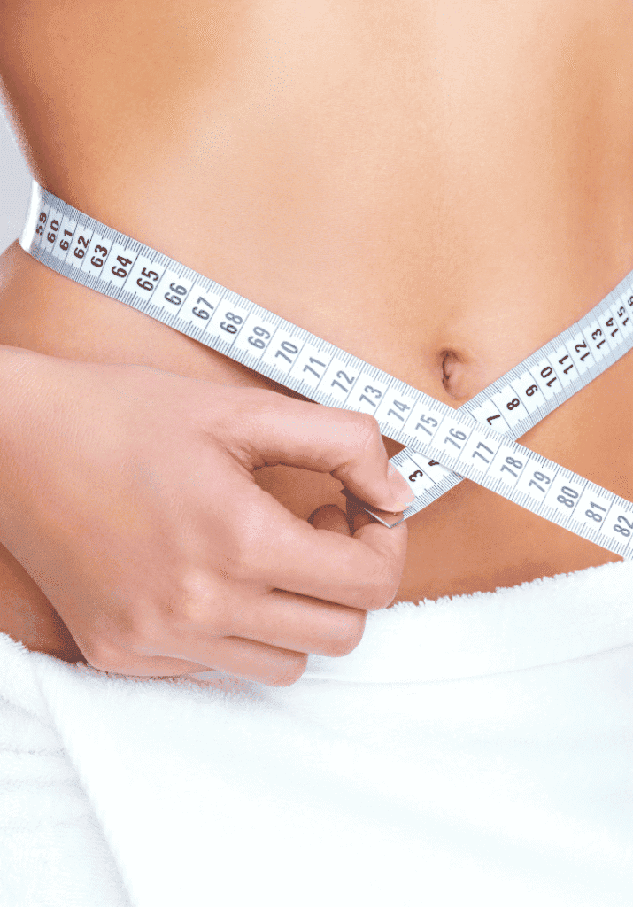  a woman measuring her waistline. 