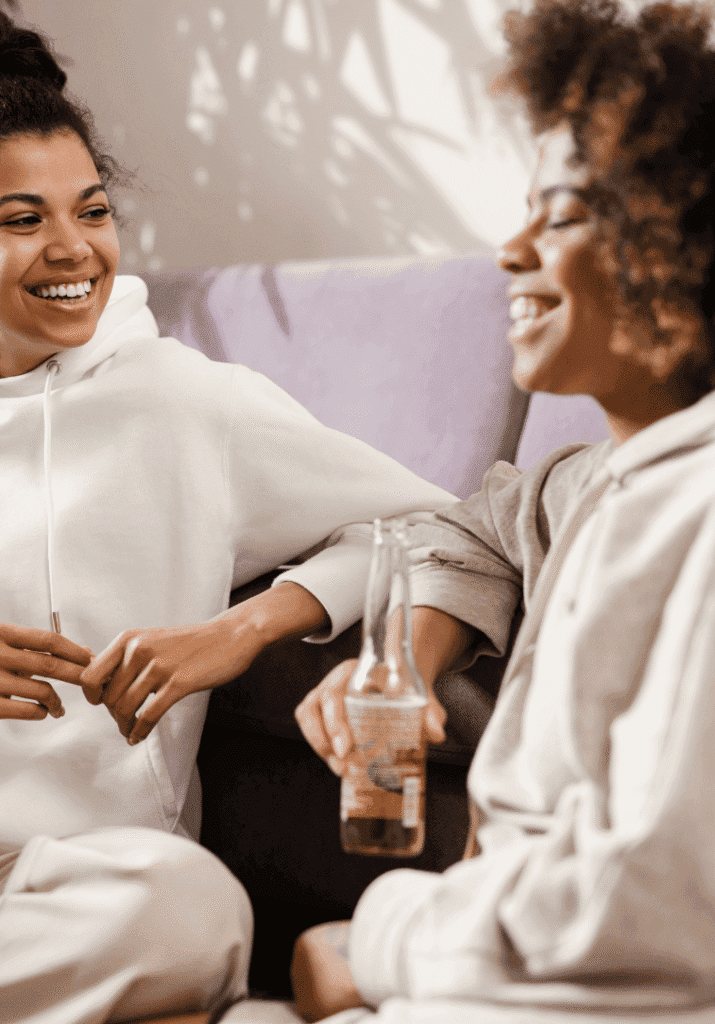 Two women on couch laughing and talking participating in mindful consumerism
