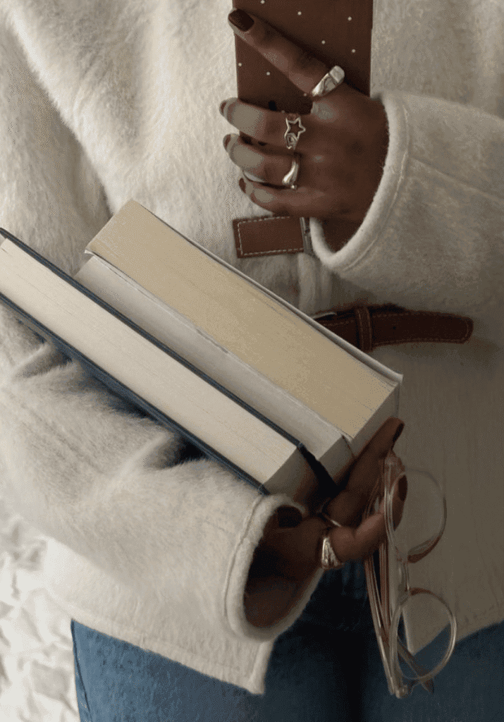 a black girl holding a lot of books and her cell phone