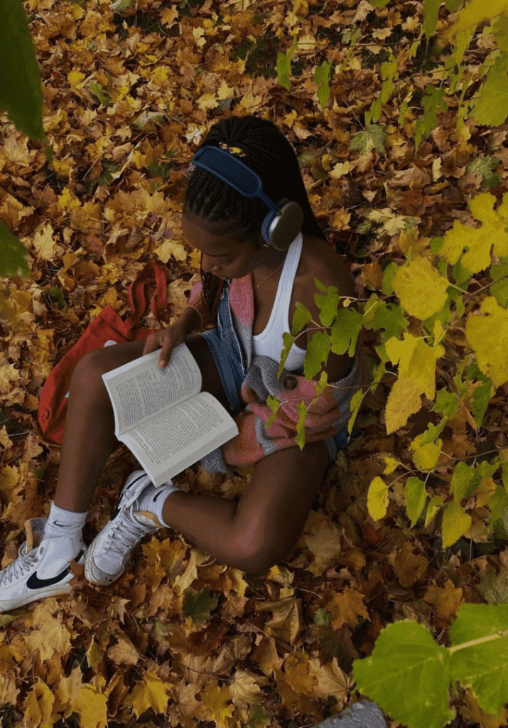 Black woman reading a fantasy book outside during a cozy afternoon
